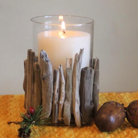 A lit candle in a driftwood candle holder on a placemat.