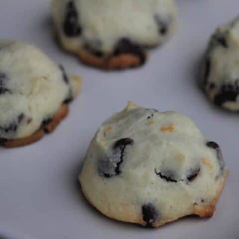 Close up of orange chocolate chip cookie on a white plate.