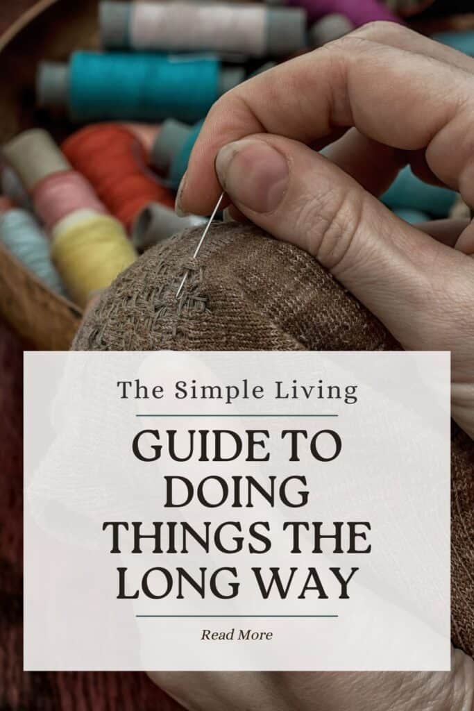 A woman's hand holds a sewing needle as she mends some cloth. Text overlay reads: The Simple Living Guide to Doing Things the Long Way. 