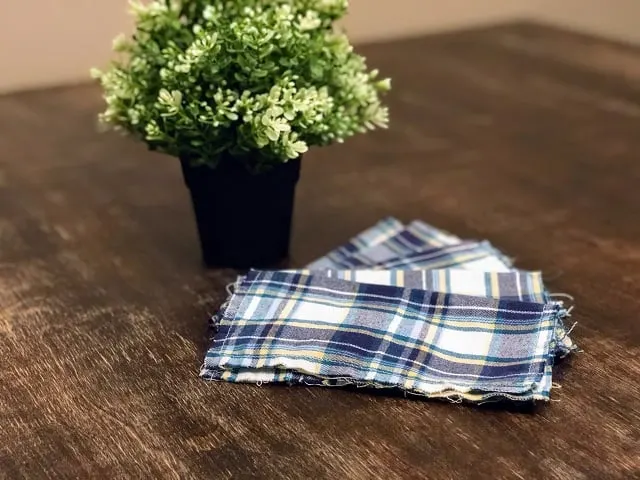 A stack of upcycled flannel hankies on a table with potted plant. 