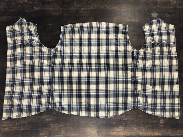 A flannel shirt laying flat after having sleeves and collar removed.