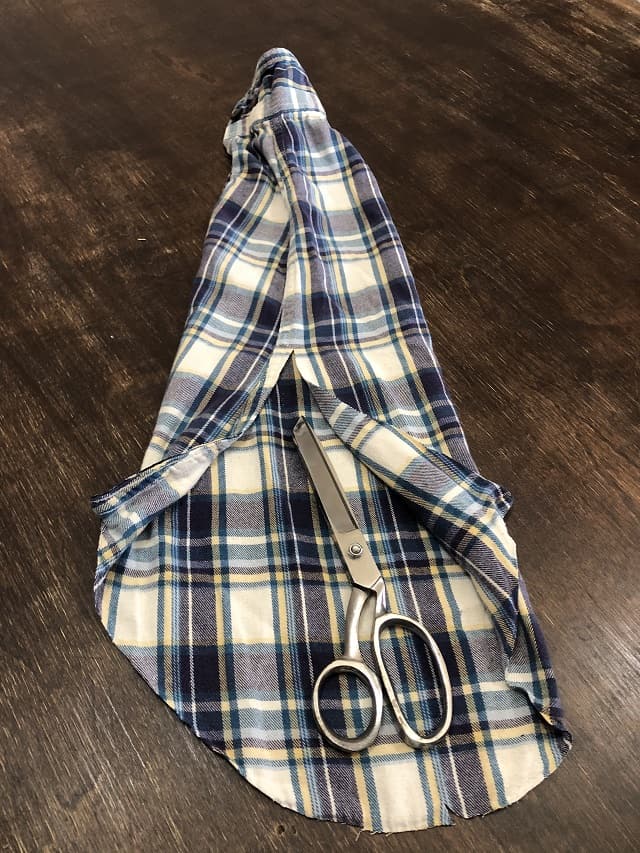 A flannel shirt sleeve being cut down the middle.