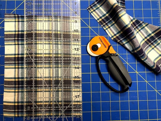 Pieces of flannel sitting on a cutting mat with a ruler and rotary cutter.