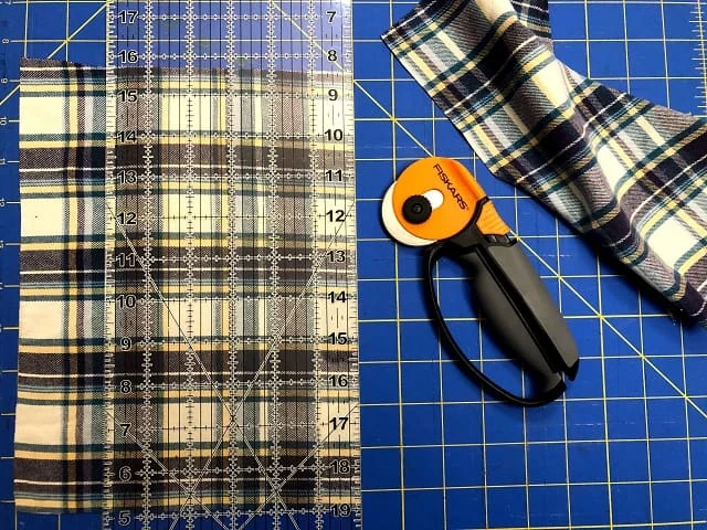 Pieces of flannel sitting on a cutting mat with a ruler and rotary cutter.