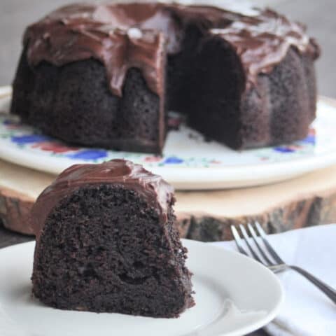 A slice of chocolate applesauce cake on a plate with a napkin and fork.