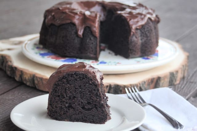 A slice of chocolate applesauce cake on a plate with a napkin and fork.