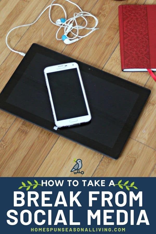 A smart phone sitting on top of a tablet with earbuds on a wooden table.