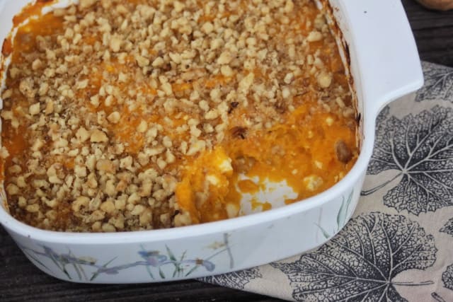 Pumpkin casserole in a pan with a spoonful missing exposing the inside.