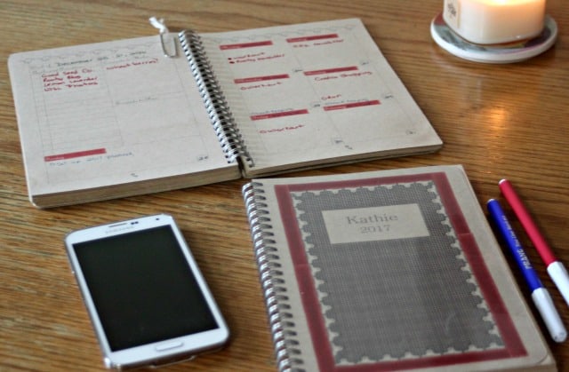 Paper planners, smart phone, and pens sitting on a work table.