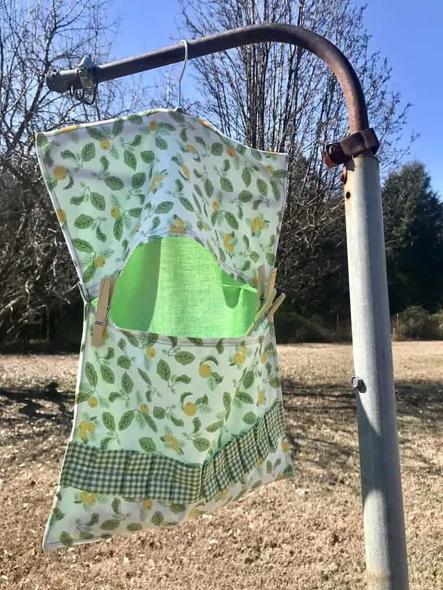 Clothespin bag hanging outside on rusty post in sunshine