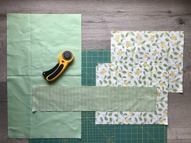 Pieces of fabric cut to size sitting on a cutting mat with rotary cutter.