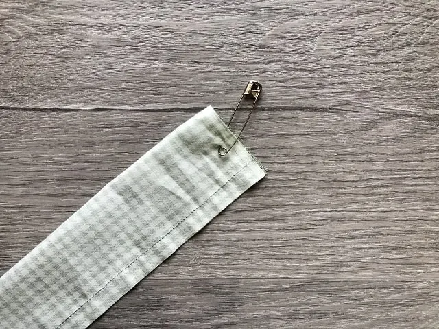 Tube of fabric with safety pin pinned to one end