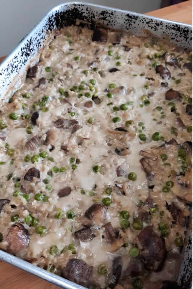 Beef casserole with peas and mushrooms in a metal pan.