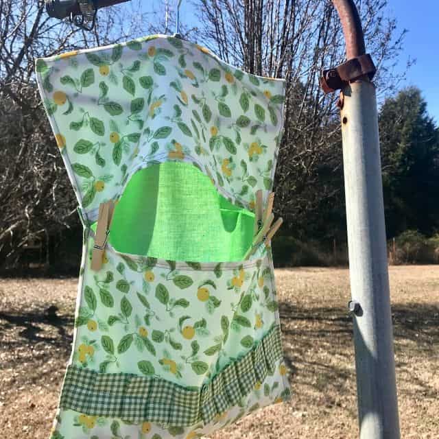 Clothespin bag hanging from rusty pole outside.