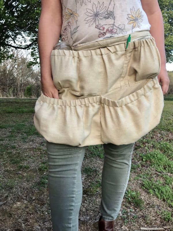 Woman standing wearing foraging apron with large elastic pockets