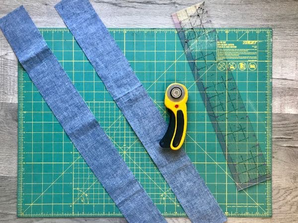 Cut fabric strips with rotary cutter laying on cutting mat