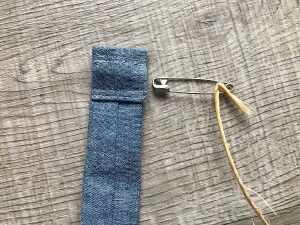 Safety pin attached to twine being inserted in fabric pocket