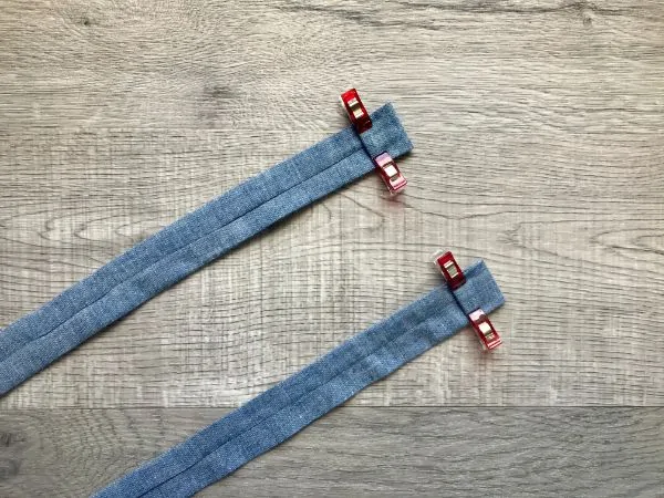 Two fabric strips with the ends folded under twice and held with clips