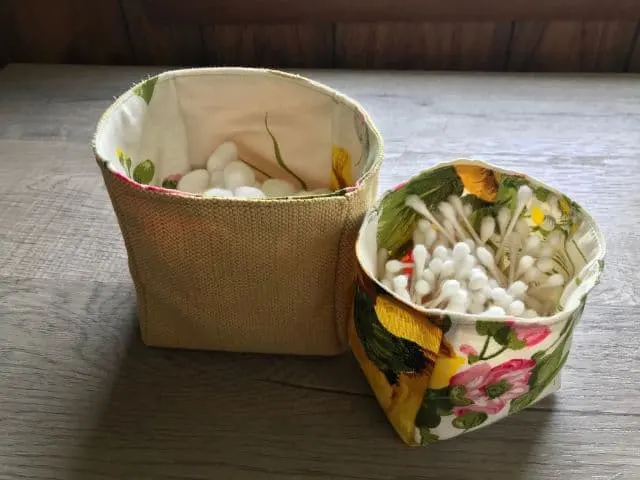 Two fabric baskets, one holding cotton balls and one holding cotton swabs.