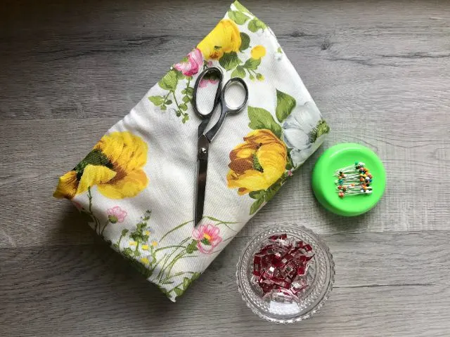 Vintage upholstery fabric with yellow and pink flowers, scissors, straight pins, sewing clips