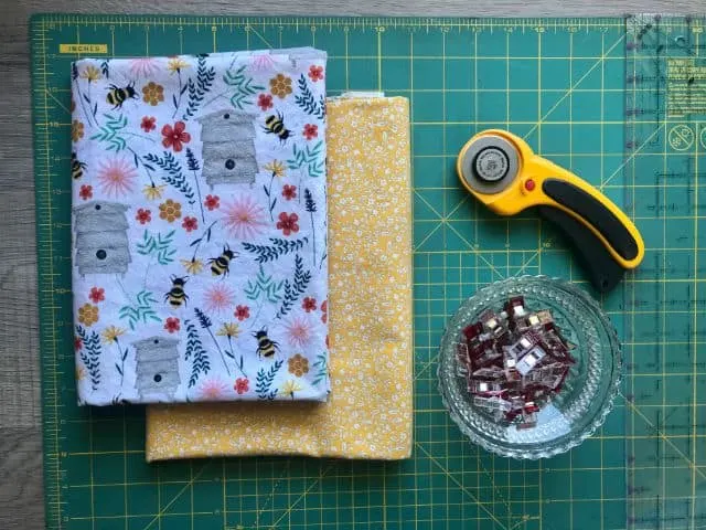 Two printed cotton fabrics, rotary cutter, sewing clips, acrylic ruler, cutting mat