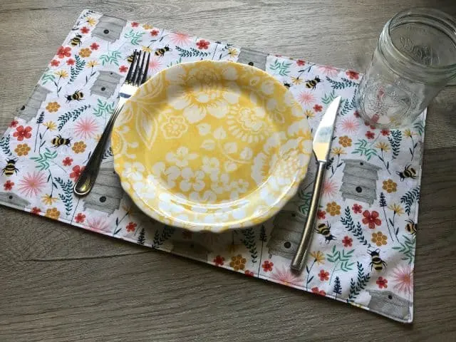 Fabric placemat featuring flowers and bees print with place setting