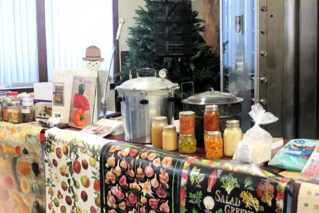 Display of canning, canning jars, and food preservation books on a table.