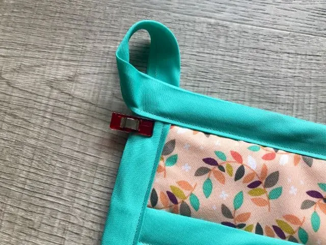 Bias tape tail turned into a loop and held to the back side of pot holder with a sewing clip