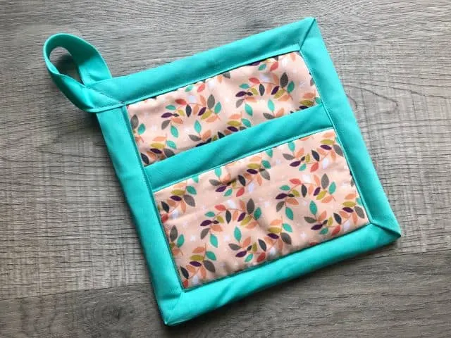 Completed hot pad with leaf print, teal bias tape and hanging loop