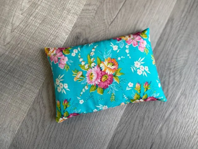 Teal floral fabric rectangle pouch filled with rice