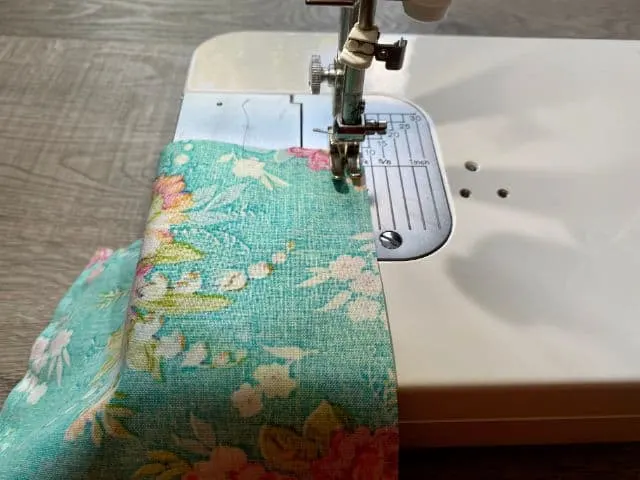 Sewing machine stitching teal floral fabric