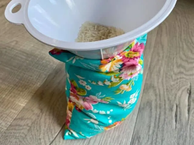 Funnel inserted in homemade heating pad being filled with rice