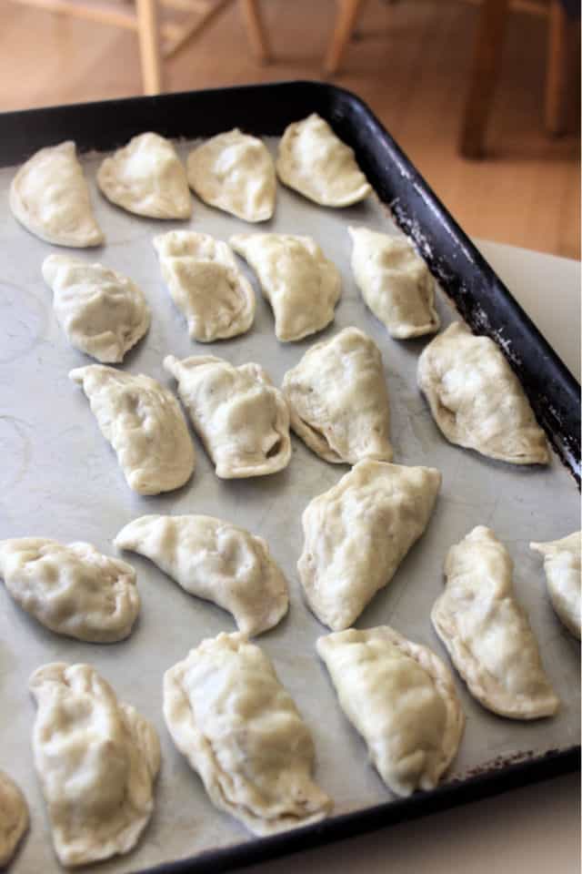 Frozen bacon cabbage pierogies lined up on a cookie sheet.