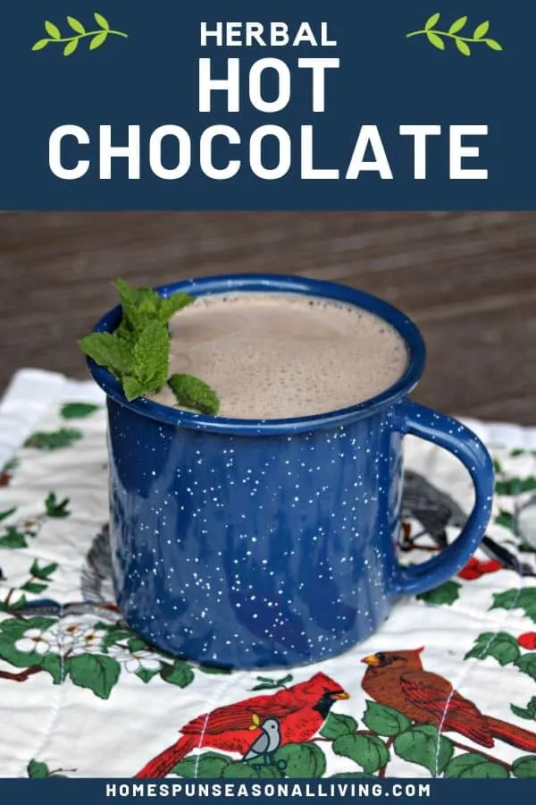A blue tin cup full of hot chocolate decorated with fresh sprigs of mint sitting on a floral and bird covered placemat with text overlay stating: herbal hot chocolate.