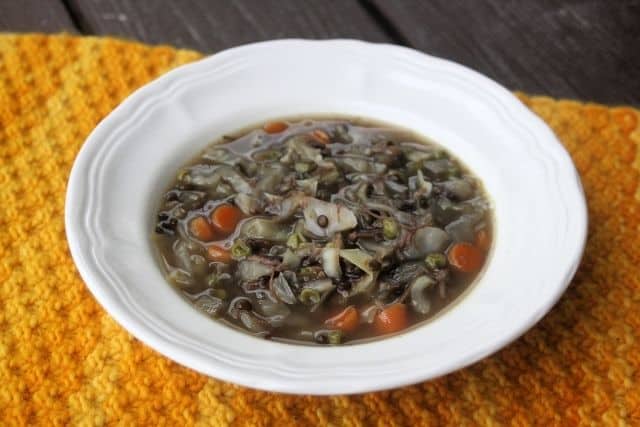 A white bowl of cabbage lentil soup as seen from above sitting on an orange placemat.