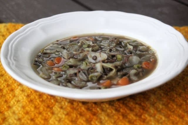 A white bowl of cabbage lentil soup sitting on an orange placemat.