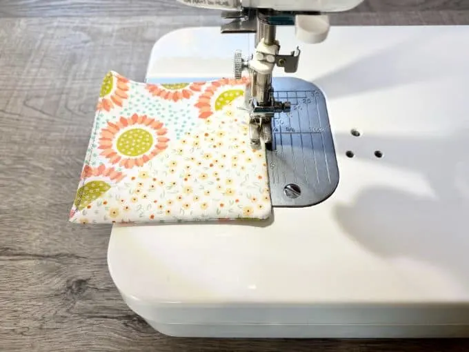Sewing machine top stitching around fabric corner bookmark with flowers