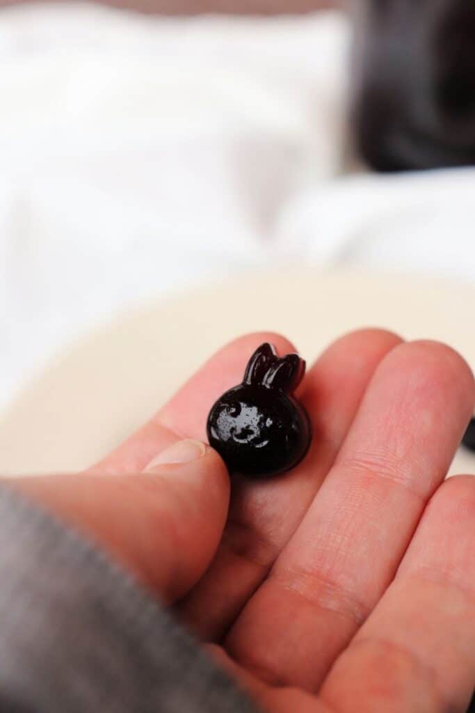 A purple bunny shaped gummie in a woman's hand.