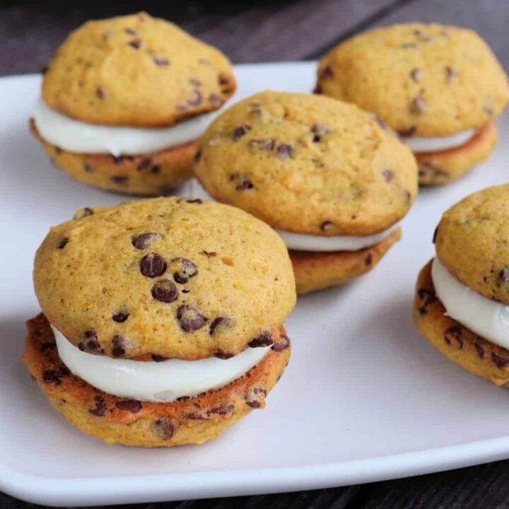 A white plate full of pumpkin chocolate chip whoopie pies.