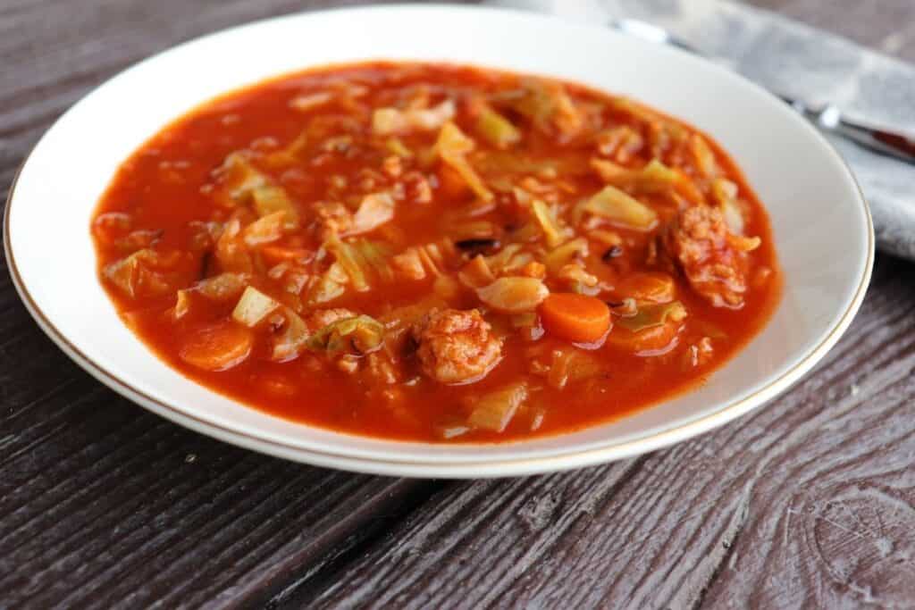 A white bowl full of cabbage roll soup as seen from the side. 