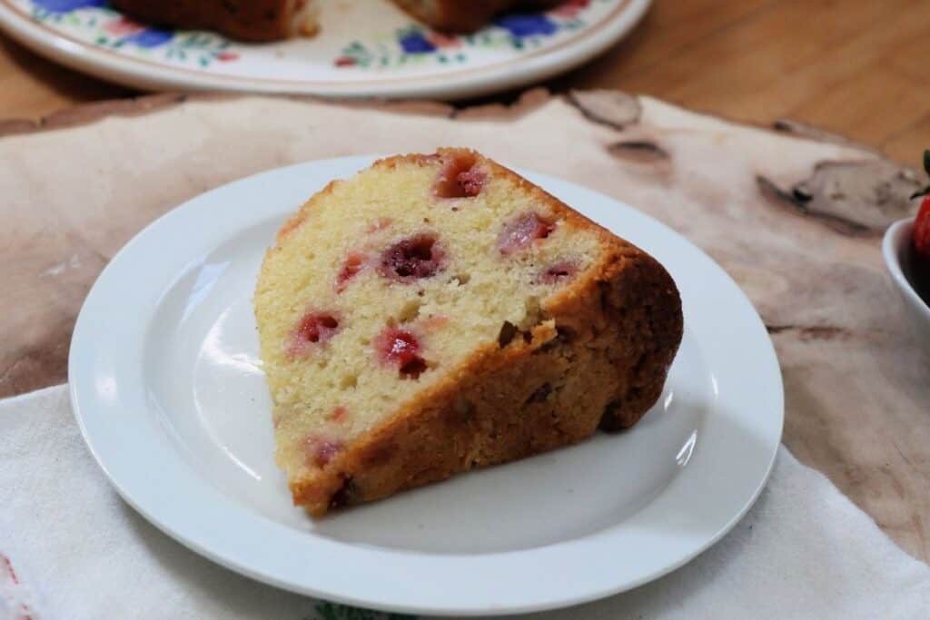 A slice of strawberry bundt cake sitting on a white plate.