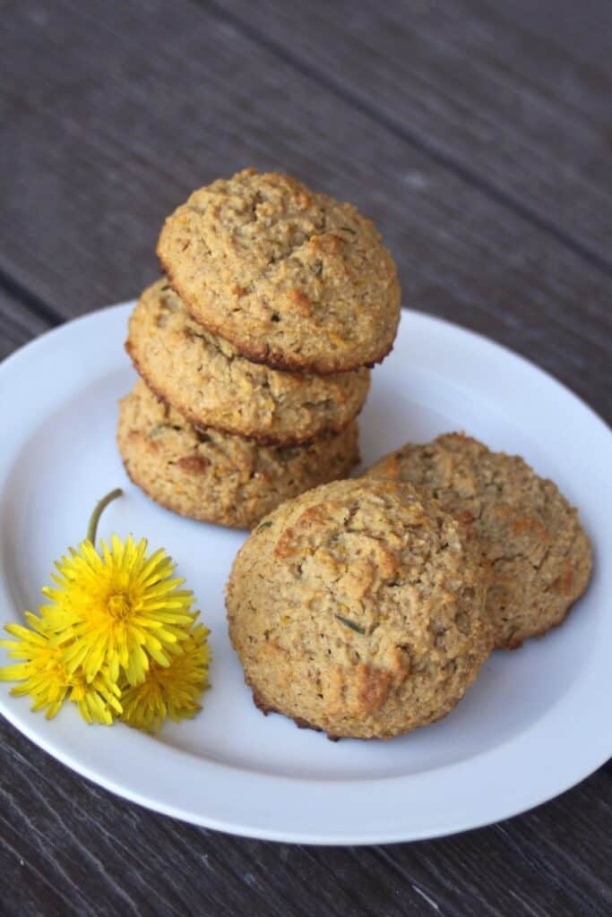 Cookies stacked on a plate with fresh dandelions flowers sitting on it. 
