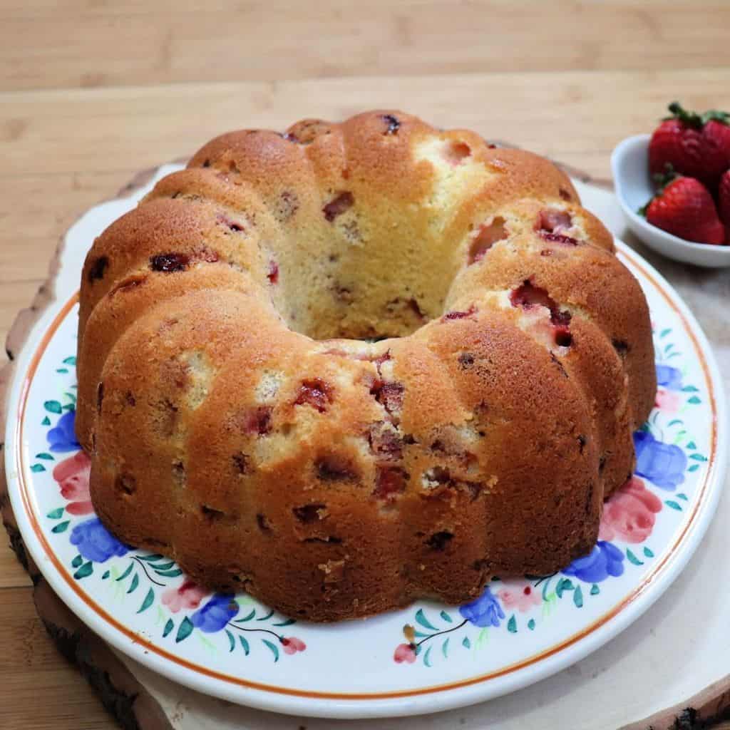 A whole strawberry bundt cake on a floral cake plate.