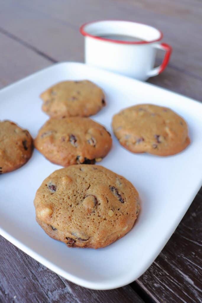 Hermit cookies on a square white plate with a cup of coffee in the background.