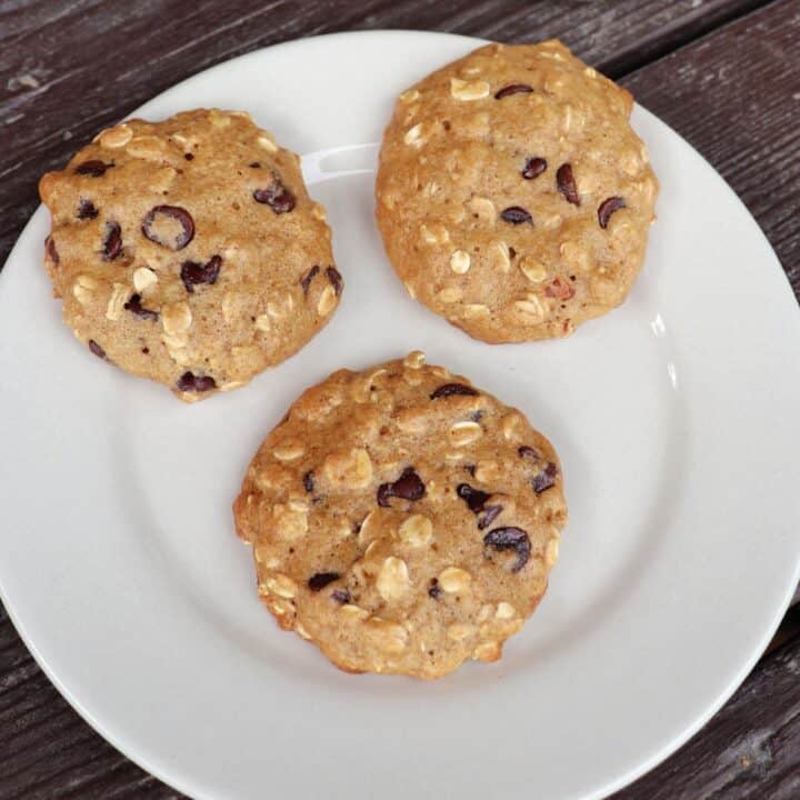 3 applesauce chocolate chip cookies scattered on a white plate as seen from above.