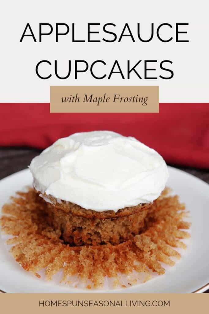 A frosted cupcake sitting on its paper liner on top of a plate with text overlay reading: Applesauce Cupcakes with Maple Frosting.
