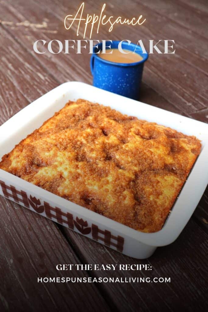 A streusel topped coffee cake in a white square pan with a blue tin cup of coffee behind it. Text overlay reads: Applesauce Coffee Cake.