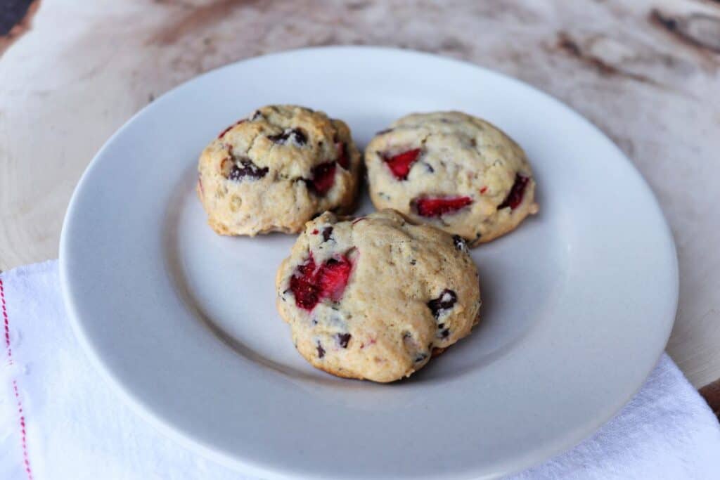 3 lavender strawberry cookies with chocolate chips sitting on a white plate.