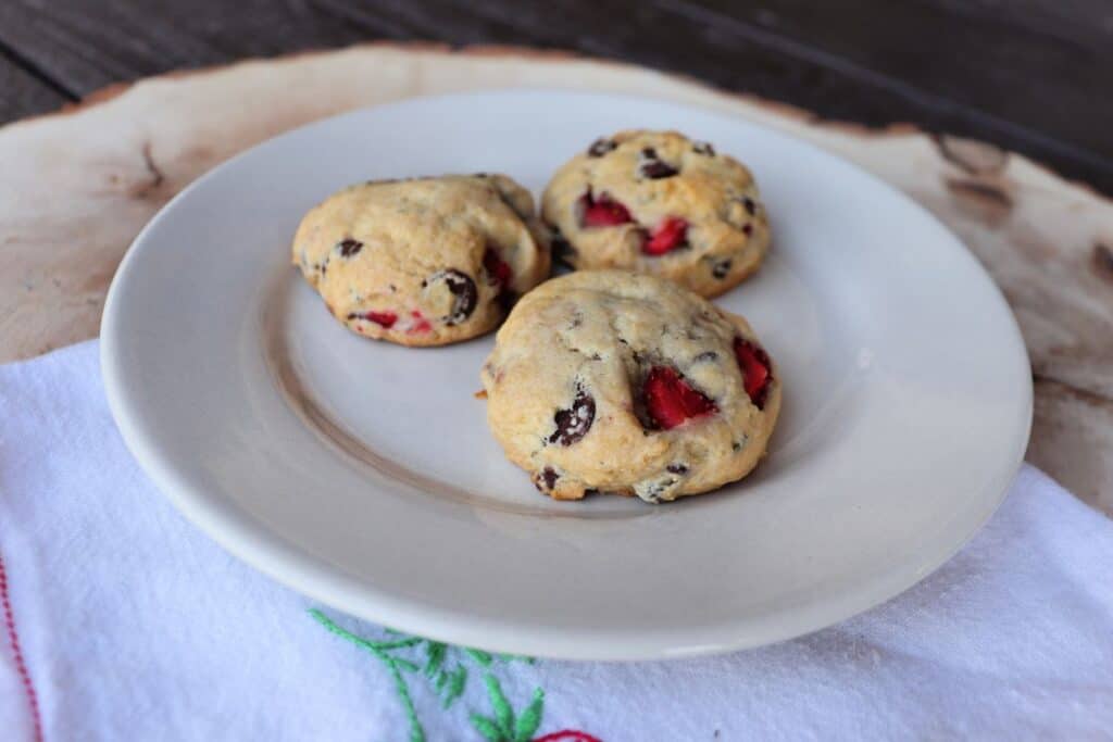 3 lavender strawberry cookies with chocolate chips sitting on a white plate.