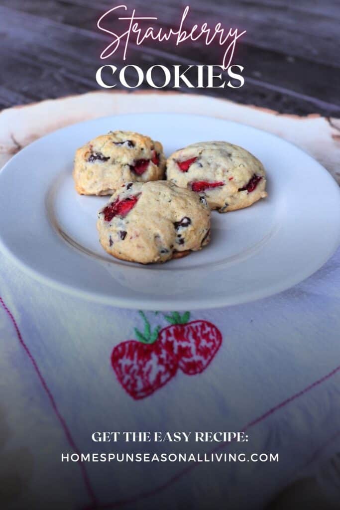 3 cookies on a plate that is sitting on a napkin with strawberries embroidered on it. Text overlay reads: Strawberry Cookies.